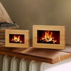 two wooden frames with fire burning in them on a table next to a radiator