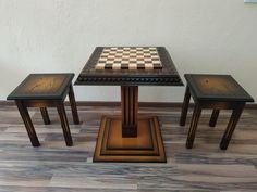 three small tables and two stools with chess board on the top, in front of a white wall