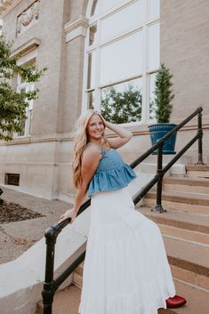 a woman in a white dress standing on some steps with her hand on her head