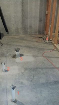 an unfinished room with some electrical equipment in the floor and on the wall, there is a heater