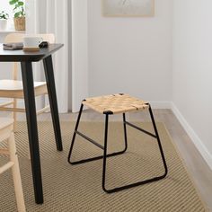 a small wooden stool sitting on top of a carpeted floor next to a table