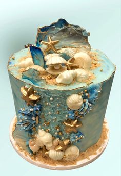 there is a blue cake with shells and starfish on the top, along with other seashells