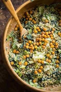 a wooden bowl filled with broccoli, chickpeas and other food items