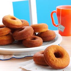 there are many doughnuts on the plate next to a coffee cup and mug