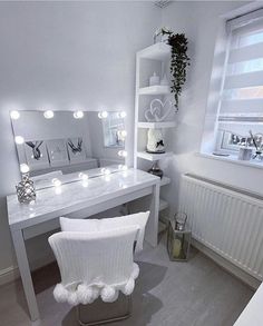 a white desk and chair in a small room with lights on the mirror above it