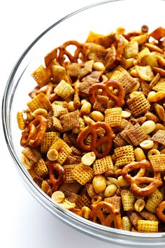 a glass bowl filled with cheetos and pretzel snack mix on top of a white table