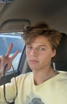 a young man sitting in the back seat of a car holding up his peace sign