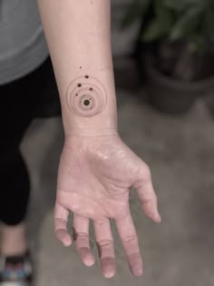 a person's hand with a small tattoo on the wrist and an object in the background