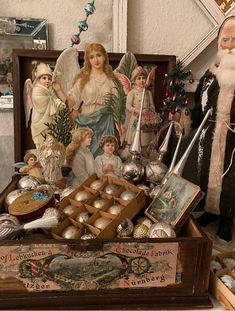 an assortment of christmas ornaments and figurines in a wooden box on a table