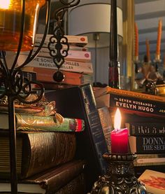 a stack of books sitting on top of a table next to a candle