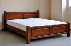 a wooden bed frame with no mattress on it in a room next to a window