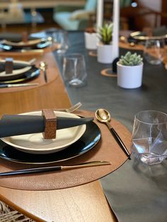 the table is set with black and white plates, utensils and silverware