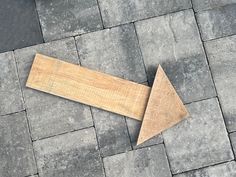 a piece of wood laying on top of a stone floor next to a wooden arrow