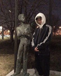 a young man standing next to a statue