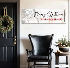 a black leather chair sitting in front of a christmas sign on the wall next to a door