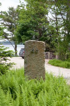 a stone marker with the number four on it in front of some plants and trees