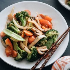 a white plate topped with vegetables and chopsticks