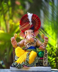 an elephant statue sitting on top of a table next to some plants and trees in the background