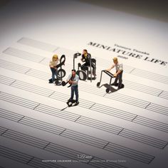 three miniature figurines sitting on top of musical notes