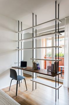 a desk and chair in front of a window with bookshelves on the wall