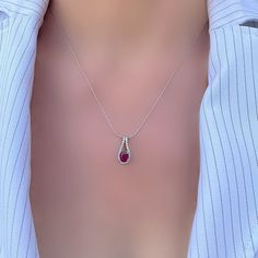 Dress up with brilliant sparkle and chic red colour with this glamorous 925 silver pear shaped cut out pendant. This cut out silver pendant with a central genuine ruby is surrounded by a halo of white topaz pavé set stones for a look so perfectly beautiful it's instantly classic. Available with a 16'', 18'' and 20'' silver platinum finish chain. Matching earrings available. Measures  8 mm by 17 mm. Available in emerald and blue sapphire stones Rubies often contain inclusions. These flaws are not looked upon as negative attributes for rubies.  Indeed, these inclusions are considered part of the character of the stone and are used to assure the purchaser of a natural stone. USPS & other international postal services are no longer guaranteeing arrival times, therefore, delays are possible. Pl Ruby Necklace Designs, Sapphire Stones, Ruby Necklace, Red Colour, Sapphire Necklace, Sapphire Stone, Silver Pendant Necklace, White Topaz, Necklace Designs