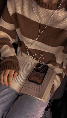 a person sitting down reading a book with headphones on