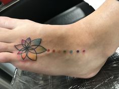 a woman's foot with a flower tattoo on her left side and dots in the middle