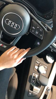 a woman is holding the steering wheel and pressing buttons on her car's dashboard