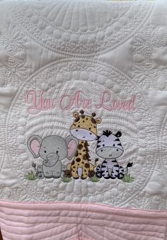 a baby quilt with an elephant, giraffe and zebra on it's side