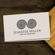 a business card with an image of two spirals in the center on top of a wooden table