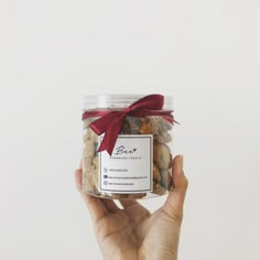 a hand holding a jar filled with nuts