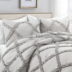 the comforter is made up with ruffled trims and white sheets, along with pillows