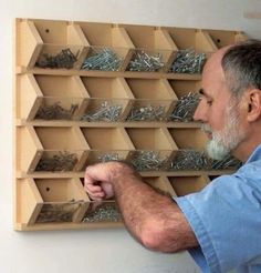 a man is looking at screws in a box on the wall and he is fixing them