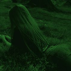 a woman with long hair sitting in the grass