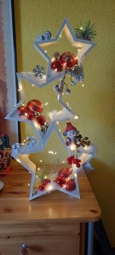 a christmas tree made out of ornaments on a wooden table with a yellow wall in the background