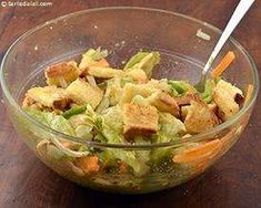 a glass bowl filled with salad on top of a wooden table