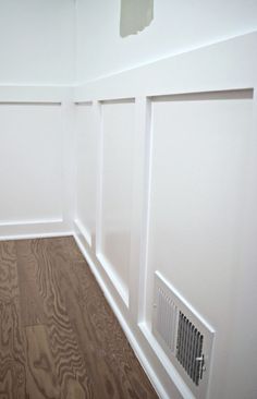 empty room with white walls and wood flooring in the corner, showing radiator