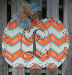 an orange and white pumpkin with a monogrammed letter on it, sitting next to a wooden fence