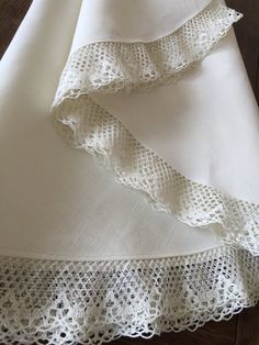 two white linens with crocheted edges on a wooden floor, next to each other