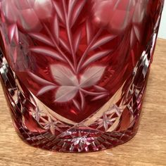 a red glass vase sitting on top of a wooden table