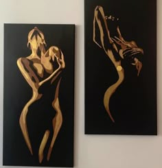 two black and gold paintings hanging on the wall