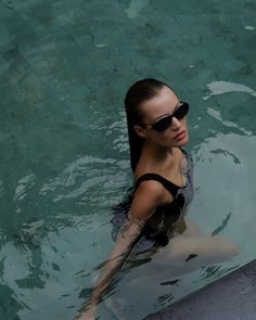 a woman is in the water wearing sunglasses