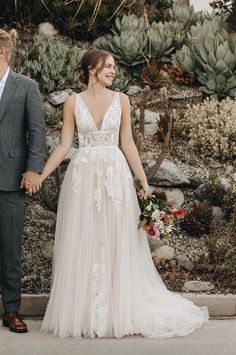 a bride and groom holding hands in front of a cactus wall with succulents