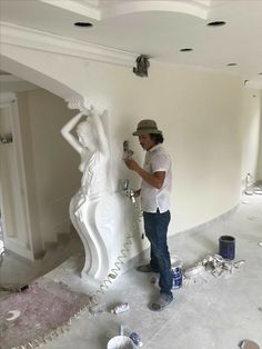 a man is painting a statue in the middle of a room with white paint on it