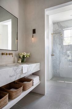 a bathroom with marble counter tops and white walls, along with baskets on the floor