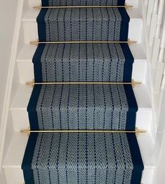 blue carpeted stairs with gold railings and handrails in a home hallway