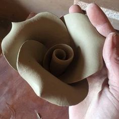 a person is holding a paper flower in their hand and it looks like they are making something out of clay