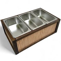 three pans sitting on top of a wooden box with metal lids in the shape of a rectangle