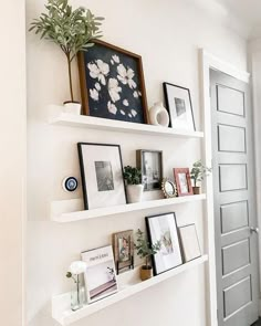 some white shelves with pictures and plants on them