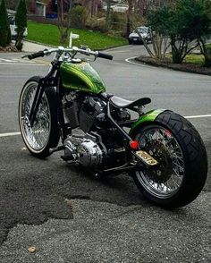 a green and black motorcycle parked in a parking lot next to a street with houses